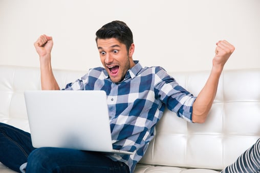 Portrait of excited man looking game on laptop at home